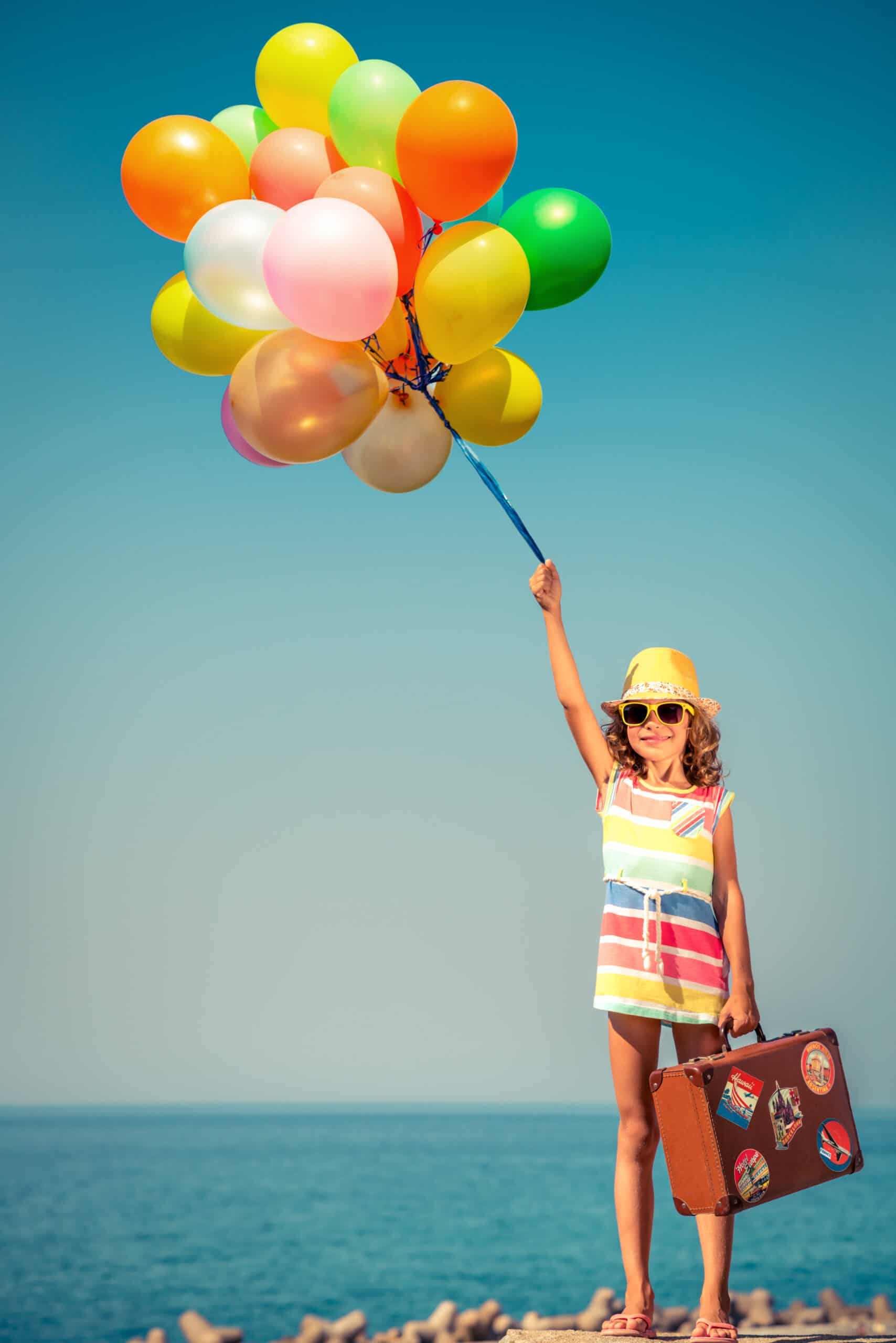 Happy,Child,Flying,With,Colorful,Balloons.,Girl,Against,Blue,Sea